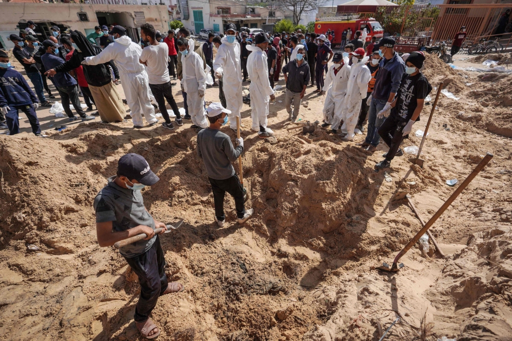 Palestinian health workers dig for bodies buried by Israeli forces in Nasser hospital compound in Khan Yunis in the southern Gaza Strip on April 21, 2024, as battles continue between Hamas militants and Israeli forces in the besieged Palestinian territory. (Photo by AFP)
