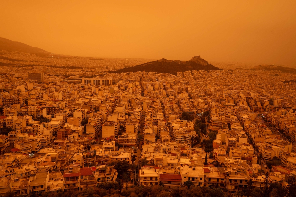 This photograph taken on April 23, 2024, in Athens shows a view of the city of Athens shrouded in haze, as southerly winds carried waves of dust to the city. (Photo by Angelos TZORTZINIS / AFP)
