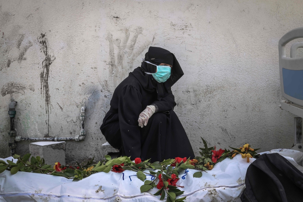 A woman mourns by a body unearthed at Nasser Hospital in Khan Yunis in the southern Gaza Strip on April 23, 2024. (Photo by AFP)
