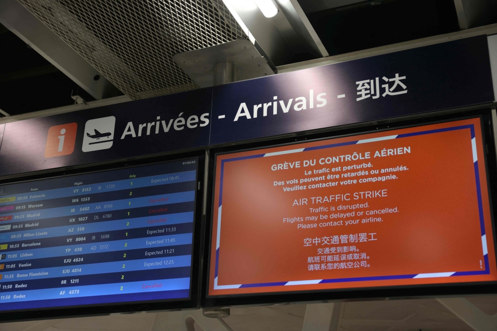 This photograph taken an April 25, 2024, shows a notice board announcing the strike next to a flights boards due to the air traffic controllers' strike, outside Paris. (Photo by Thomas Samson / AFP)