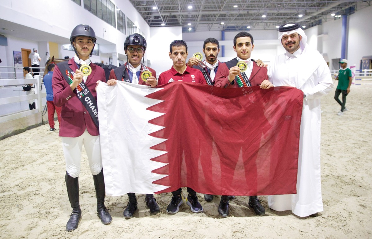 Qatar equestrian team's riders and Director of the Qatar Equestrian Teams Abdullah Al Marri pose with the national flag.   