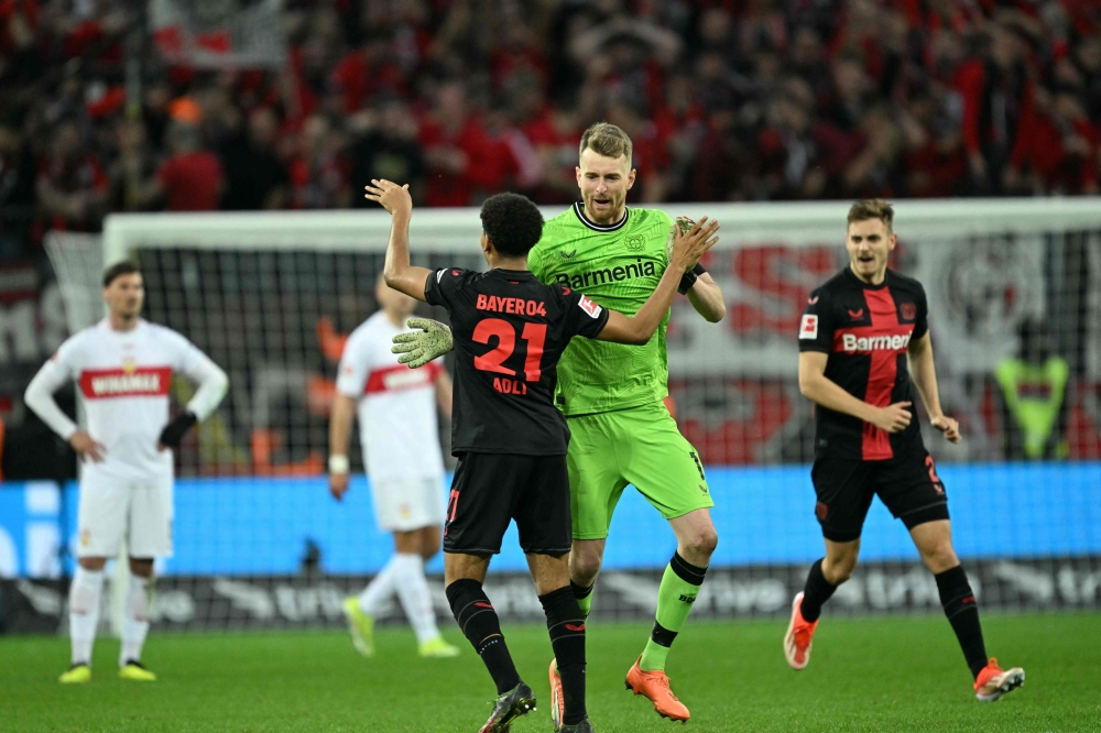 Bayer Leverkusen's Finnish goalkeeper #01 Lukas Hradecky and Bayer Leverkusen's French forward #21 Amine Adli celebrate after the German first division Bundesliga football match Bayer 04 Leverkusen v VfL Stuttgart in Leverkusen, western Germany, on April 27, 2024. (Photo by INA FASSBENDER / AFP) 
