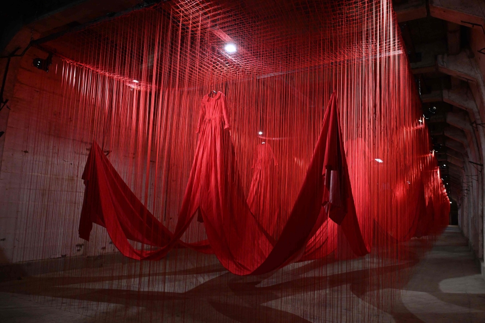 An installation of red ropes and empty dresses floats in the tunnel of the former concentration camp of Ebensee in the Salzkammergut region, 250 km west of Vienna, Austria, on April 26, 2024, during the opening of Japanese artist Chiharu Shiota's exhibition. Photo by KERSTIN JOENSSON / AFP.