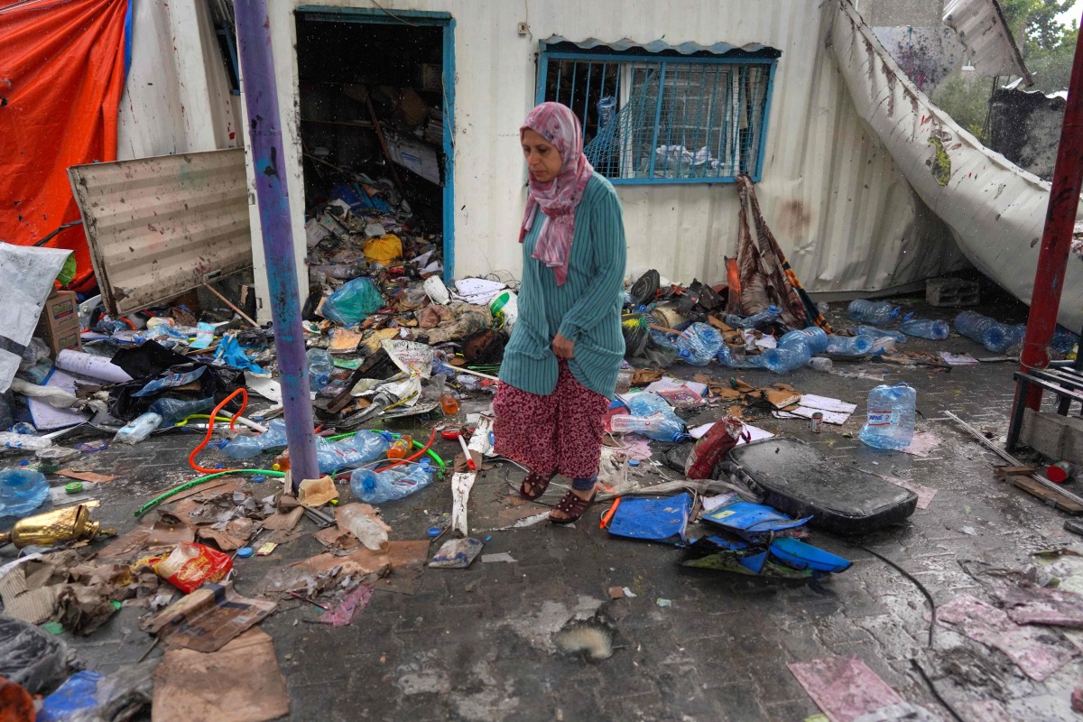A Palestinian woman inspects the debris of a container at an UNRWA school used to shelter displaced people, after it was hit in Israeli bombardment on Nusseirat in the central Gaza Strip on May 6, 2024. (Photo by AFP)
