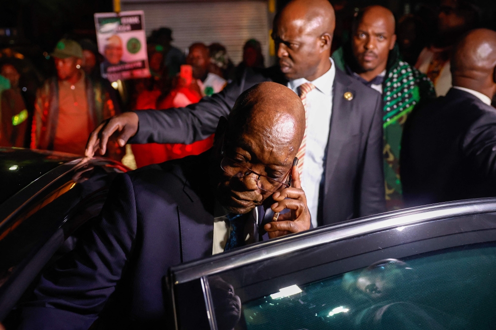 Former South African President and leader of the newly-formed uMkhonto we Sizwe (MK) Party, Jacob Zuma (C) calls with his smartphone after the Constitutional Court hearing over his eligibility to stand for parliament, in Johannesburg on May 10, 2024. (Photo by Phill Magakoe / AFP)
