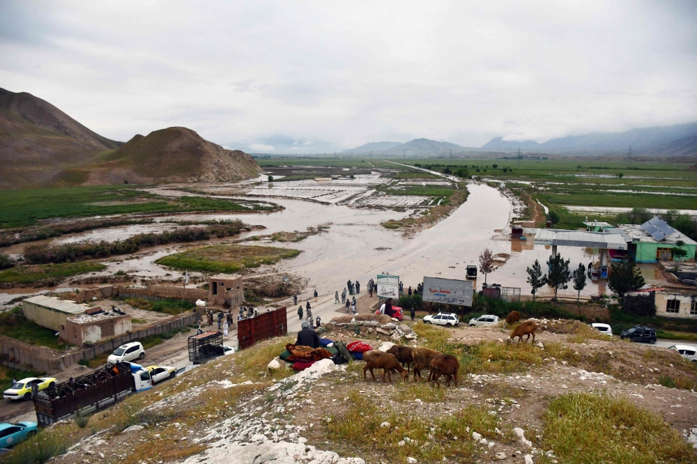 Afghan people gather along a road before a floaded area between Samangan and Mazar-i-Sharif following a flash flood after a heavy rainfall in Feroz Nakhchir district of Samangan Province on May 11, 2024. (Photo by Atif Aryan / AFP)
 