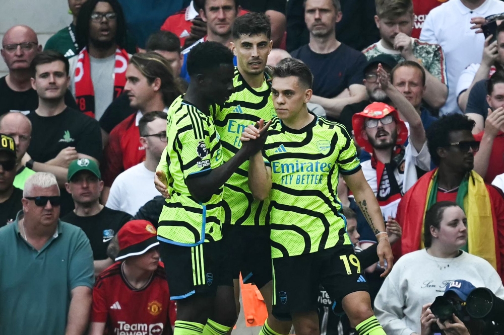 Arsenal's Belgian midfielder #19 Leandro Trossard (R) celebrates scoring the team's first goal during the English Premier League football match between Manchester United and Arsenal at Old Trafford in Manchester, north west England, on May 12, 2024. (Photo by Paul ELLIS / AFP) 