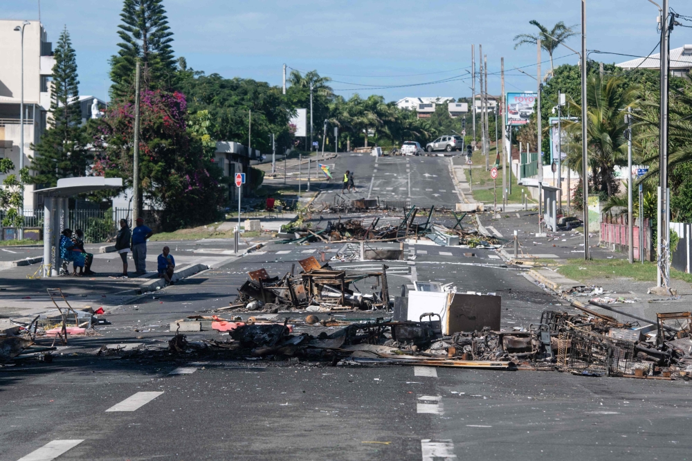 A street blocked by debris and burnt out items is seen following overnight unrest in the Magenta district of Noumea, France's Pacific territory of New Caledonia, on May 18, 2024. (Photo by Delphine Mayeur / AFP)