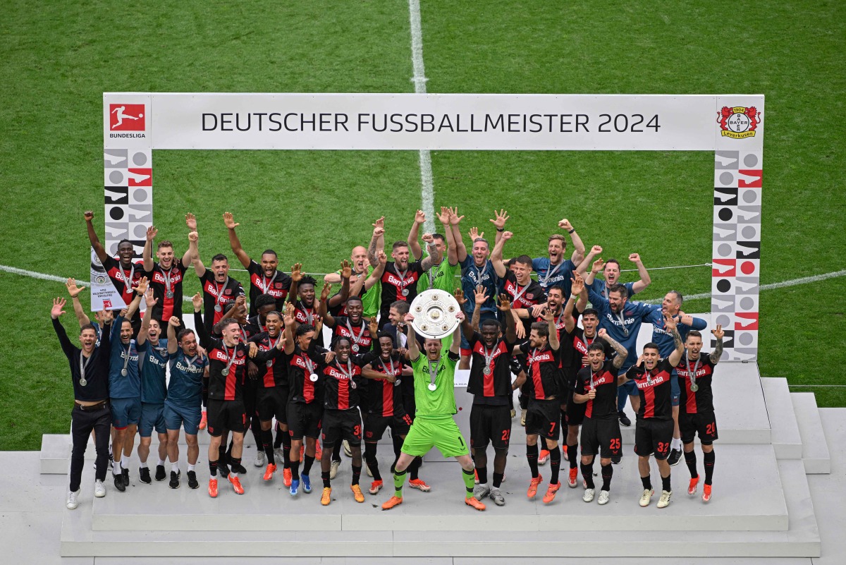 Bayer Leverkusen's Finnish goalkeeper #01 Lukas Hradecky and teammates celebrate with the trophy after the German first division Bundesliga football match between Bayer 04 Leverkusen and FC Augsburg in Leverkusen, western Germany on May 18, 2024. . (Photo by Sascha Schuermann / AFP)