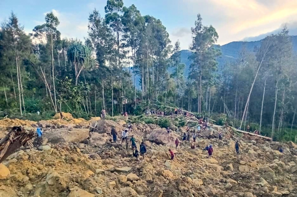 People gather at the site of a landslide in Maip Mulitaka in Papua New Guinea's Enga Province on May 24, 2024. (Photo by AFP)