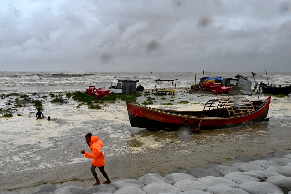A man pulls a fishing boat to a sea shore as a preventive measure during rainfall in Kuakata on May 26, 2024, ahead of cyclone Remal's landfall in Bangladesh. Cyclone Remal is set to hit the country and parts of neighbouring India on May 26 evening, with Bangladesh's weather department predicting crashing waves and howling gales with gusts of up to 130 kilometres (81 miles) per hour. (Photo by Munir Uz Zaman / AFP)