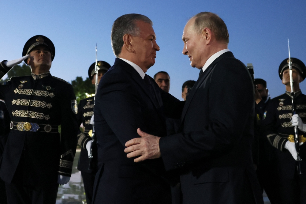 In this pool photograph distributed by the Russian state agency Sputnik, Uzbek President Shavkat Mirziyoyev welcomes Russia's President Vladimir Putin upon his arrival at the airport in Tashkent on May 26, 2024. (Photo by Mikhail Metzel / POOL / AFP) 