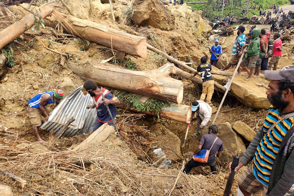 This handout photo taken and received on May 27, 2024 from the International Organization for Migration shows locals digging at the site of a landslide at Mulitaka village in the region of Maip Mulitaka, in Enga Province, Papua New Guinea. (Photo by Mohamud Omer / International Organization for Migration / AFP) 