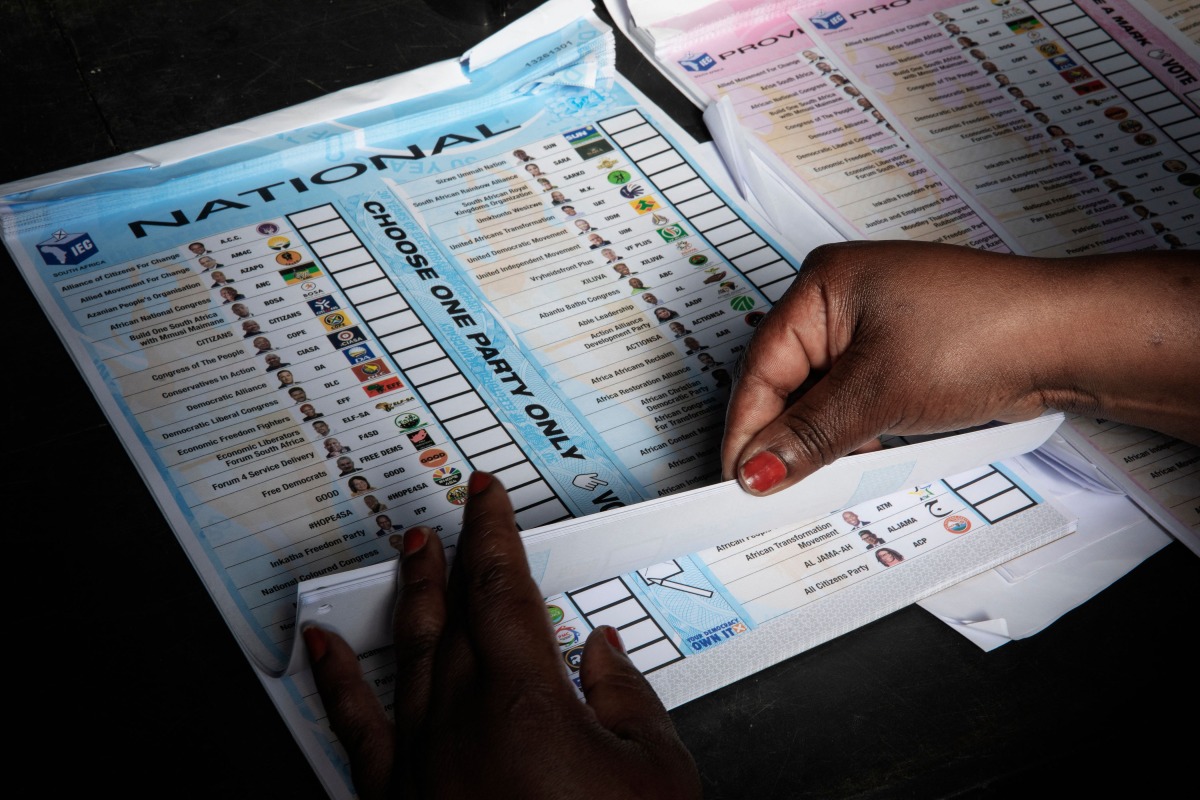 An Electoral Commission of South Africa (IEC) official prepares a ballot to be handed out to a voter during special voting at the Glebe Community Hall polling station in Umlazi on May 28, 2024 the day ahead of the South African elections scheduled for May 29, 2024. (Photo by GIANLUIGI GUERCIA / AFP)
