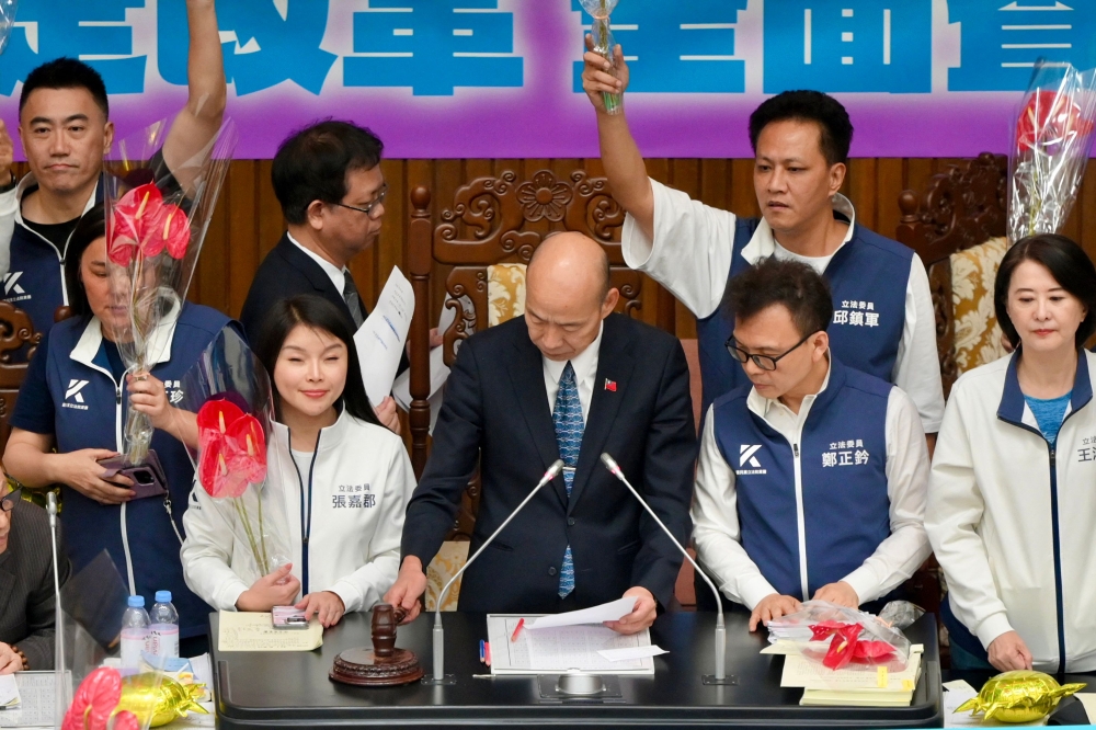 Lawmakers from main opposition Kuomintang (KMT) wave the Anthurium flowers to celebrate their victory as Parliament Speaker Han Kuo-yu (C) knocking the hammer to pass Parliament Reform Bills in Taipei on May 28, 2024. Photo by Sam Yeh / AFP.
