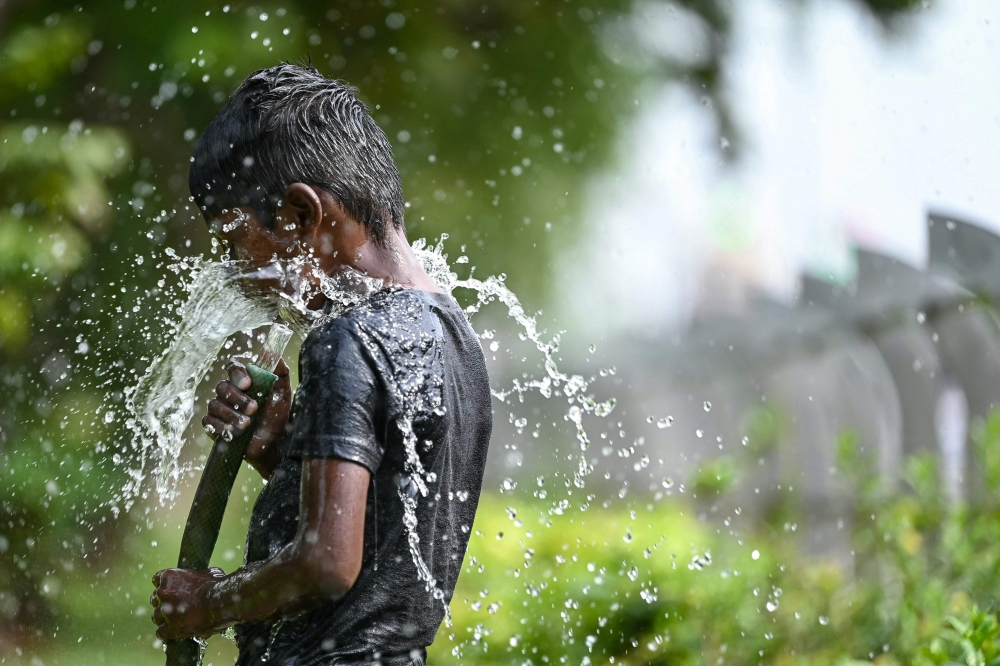 A boy plays with water during a hot summer day in Chennai on May 28, 2024. (Photo by R.Satish Babu / AFP)