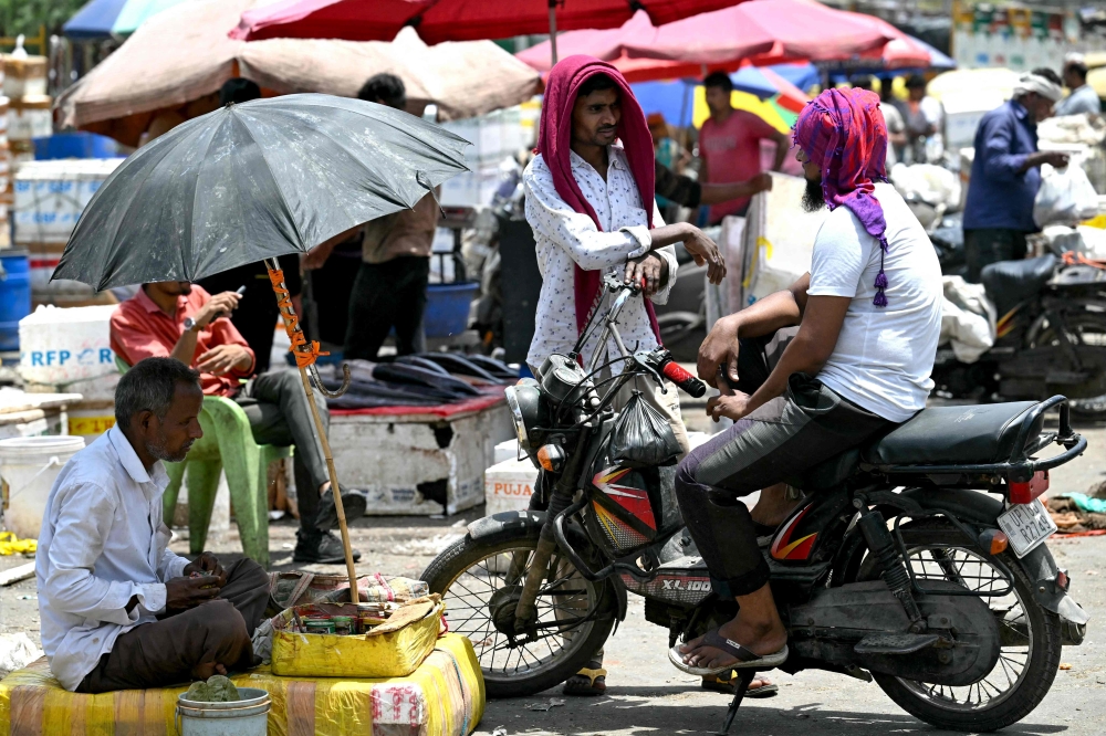 Men cover their head with cloth on a hot summer afternoon in New Delhi on May 29, 2024, amid ongoing heatwave. (Photo by Arun Sankar / AFP)
