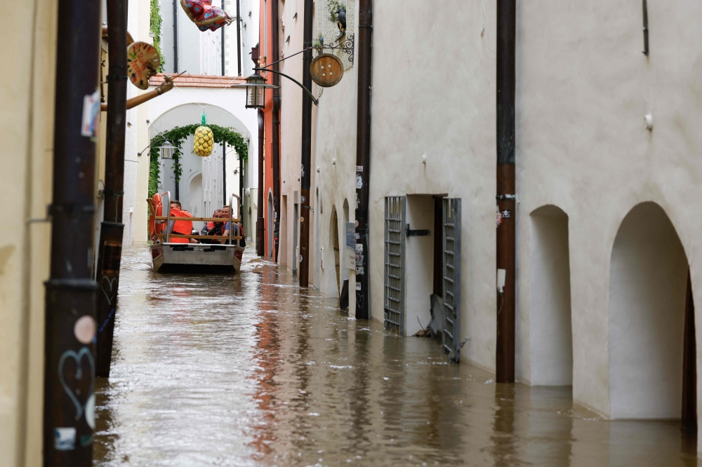 A boat with rescue helpers ships through a flooded street in the center of Passau in Bavaria, southern Germany, on June 4, 2024. Photo by Michaela STACHE / AFP