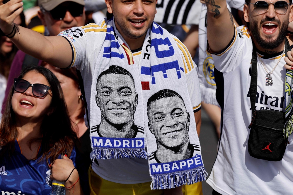 Supporters wearing football scarves depicting French footballer Kylian Mbappe cheer prior Real Madrid's celebration for winning 2024 Spanish La Liga title at Cibeles square in Madrid on May 12, 2024. Photo by OSCAR DEL POZO / AFP