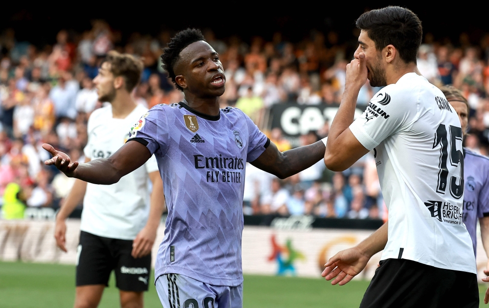 Real Madrid's Brazilian forward Vinicius Junior (L) talks to Valencia's Turkish defender Cenk Ozkacar as he reacts to being insulted from the stands during the Spanish league football match between Valencia CF and Real Madrid CF at the Mestalla stadium in Valencia on May 21, 2023. Photo by JOSE JORDAN / AFP.