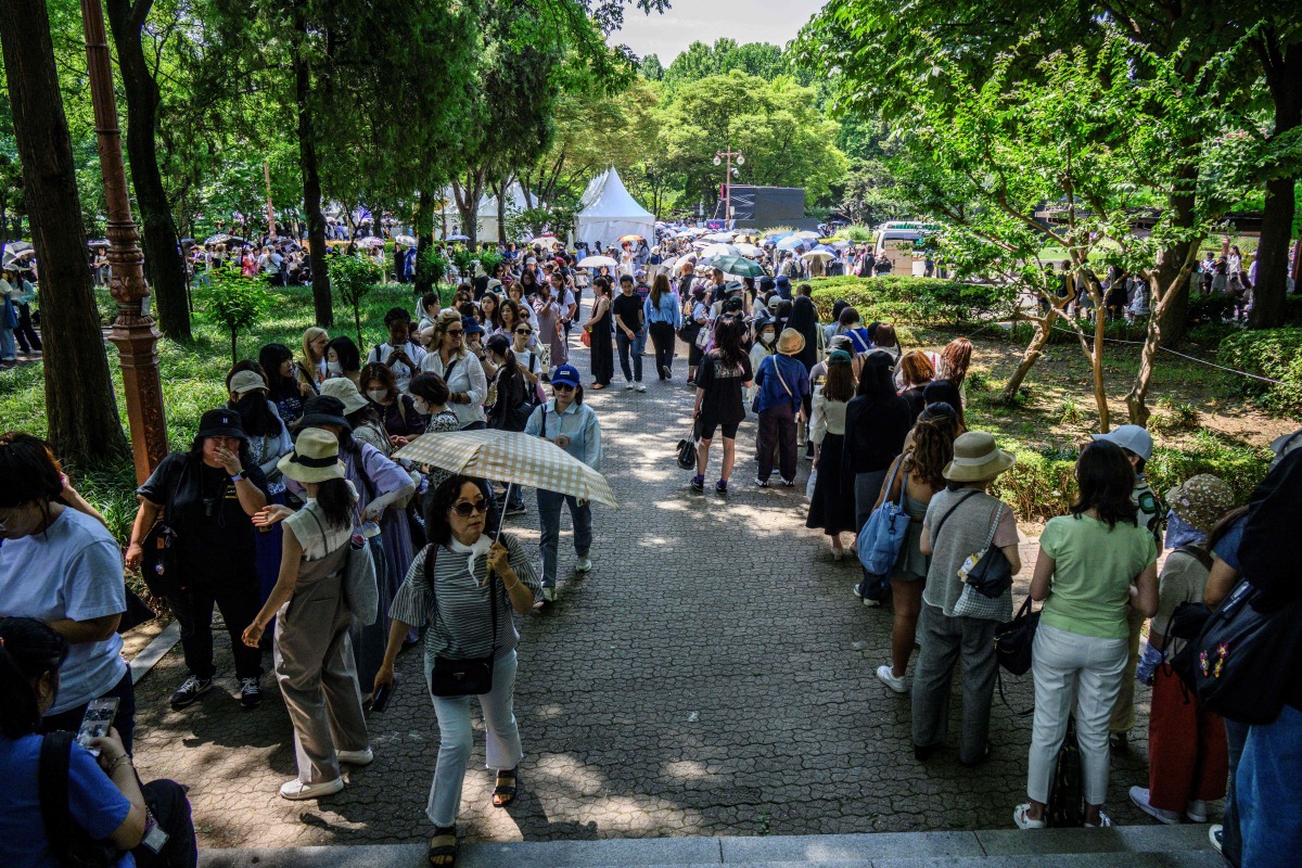 Fans of K-pop boy band BTS pose during the annual BTS FESTA, organised by HYBE, the band's agency, in Seoul on June 13, 2024. (Photo by ANTHONY WALLACE / AFP)