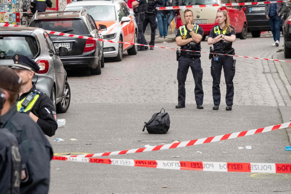 Policemen stand next to a backpack lying on the ground as they secure an area close to the Reeperbahn street and entertainment district following a police intervention on June 16, 2024, hours before the kick off for the UEFA Euro 2024 Group D football match between Poland and the Netherlands.  (Photo by Bodo Marks / dpa / AFP)
