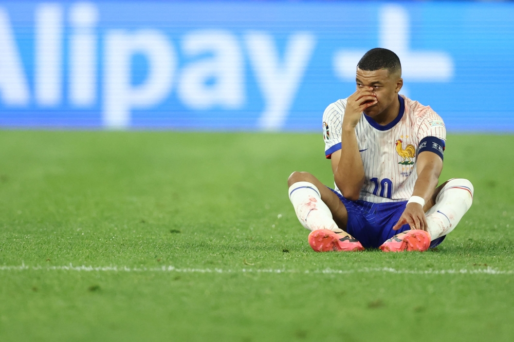 France's forward #10 Kylian Mbappe sits on the pitch after being injured during the UEFA Euro 2024 Group D football match against Austria on June 17, 2024. (Photo by Franck Fife / AFP)