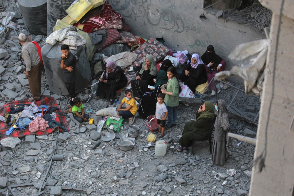Palestinians sit on the rubble during search operations following overnight Israeli strikes in al-Bureij refugee camp in the central Gaza Strip, on June 18, 2024. (Photo by Bashar Taleb / AFP)