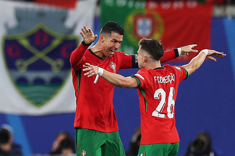 Portugal's forward #07 Cristiano Ronaldo and second goal-scorer, Portugal's forward #26 Francisco Conceicao celebrate on the pitch after the UEFA Euro 2024 Group F football match between Portugal and the Czech Republic at the Leipzig Stadium in Leipzig on June 18, 2024. (Photo by Adrian DENNIS / AFP)

