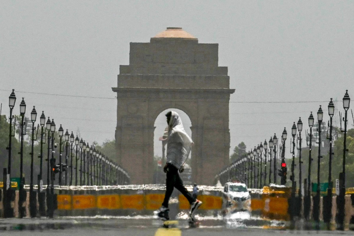 A man wears a scarf as he walks past the India Gate on a hot summer day in New Delhi on June 18, 2024. Photo by Arun SANKAR / AFP.