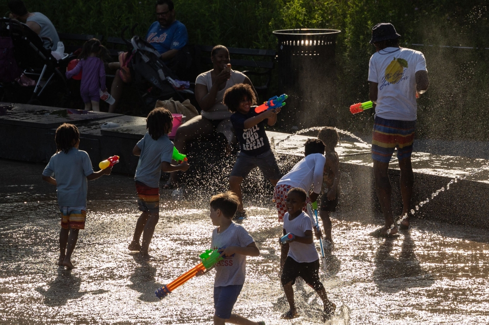 Children play with water guns at a splash pad at LeFrak Center at Lakeside at Prospect Park in Brooklyn, New York, as a heat wave hits the northeast US on June 20, 2024. (Photo by Yuki IWAMURA / AFP)
