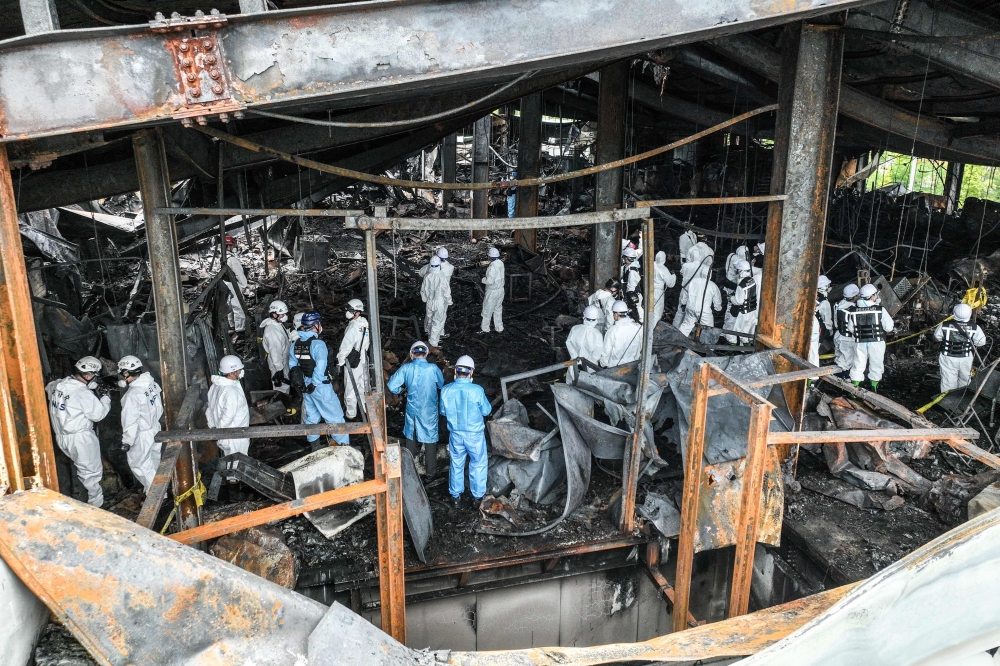 Emergency personnel and investigators examine the site the day after a fire at a lithium battery factory owned by South Korean battery maker Aricell in Hwaseong on June 25, 2024. (Photo by YONHAP / AFP) 