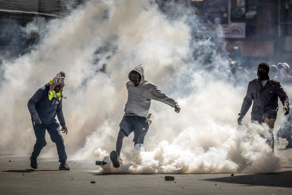 A protester kicks a tear gas canister while demonstrating during a nationwide strike to protest against tax hikes and the Finance Bill 2024 in downtown Nairobi, on June 25, 2024. (Photo by Luis Tato / AFP)