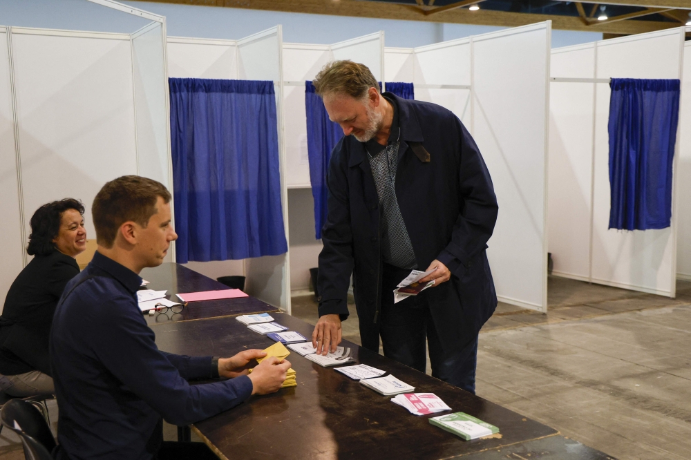 A French citizen prepares to cast his vote in the first round of parliamentary elections in Brussels, on June 30, 2024. (Photo by Nicolas Maeterlinck / BELGA / AFP)  