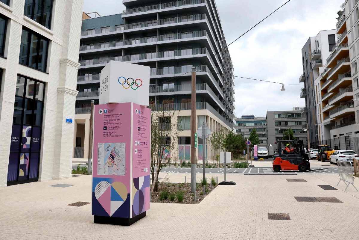 This photograph shows a direction sign at site of the Olympic village where the athletes will be housed in Saint-Denis, a nearby suburb of Paris, on July 2, 2024. (Photo by EMMANUEL DUNAND / AFP)