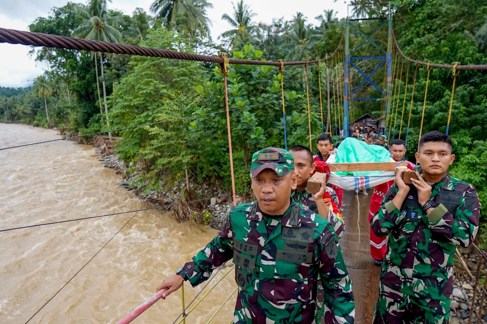Members of a rescue team carry a survivor of the landslide at Tulabolo village in Bone Bolango Regency of the Gorontalo Province on July 8, 2024. (Photo by Didot / AFP)
 