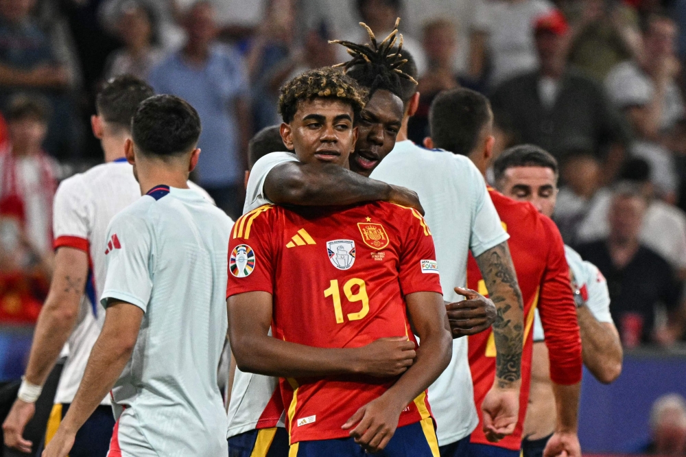 Spain's forward #19 Lamine Yamal and midfielder #17 Nico Williams celebrate their team's win at the end of the UEFA Euro 2024 semi-final football match between Spain and France at the Munich Football Arena in Munich on July 9, 2024. (Photo by JAVIER SORIANO / AFP)
