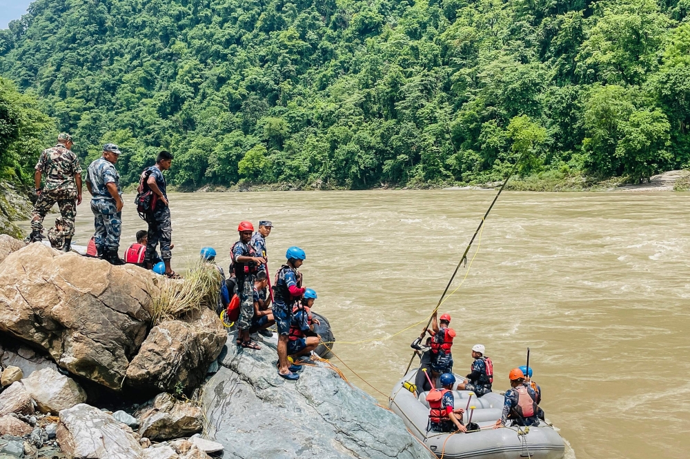 Members of Nepal's Armed Police Force (APF) search for survivors in the Trishuli River at the site of a landslide following heavy rainfall in Simaltar on July 13, 2024. (Photo by Rajesh Ghimire / AFP)