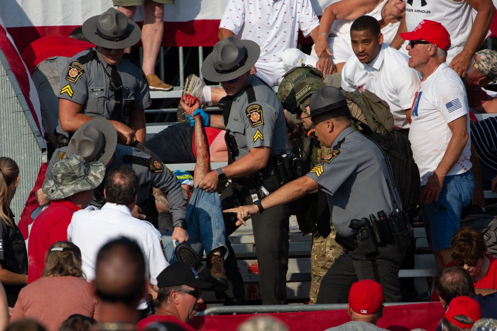 A person is removed by state police from the stands after guns were fired at Republican candidate Donald Trump at a campaign event at Butler Farm Show Inc. in Butler, Pennsylvania, July 13, 2024. (Photo by Rebecca Droke / AFP)