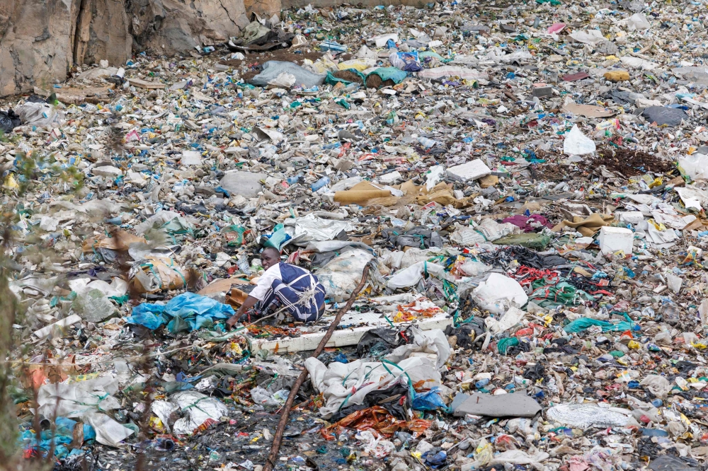 A volunteer searches through a rubbish dump for human remains at Mukuru slum in Nairobi on July 14, 2024. (Photo by Tony Karumba / AFP)
