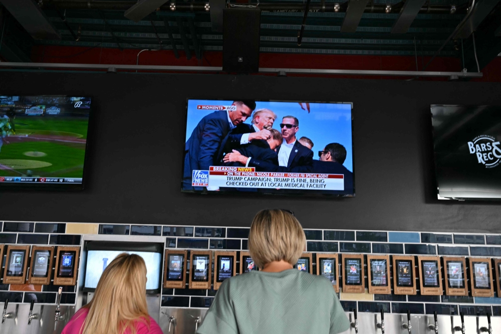 People inside the Fiserv Forum watch the news on television after hearing that Donald Trump was evacuated from the stage of his rally in Pennsylvania on July 13, 2024 in Milwaukee, Wisconsin. (Photo by Angela Weiss / AFP)

