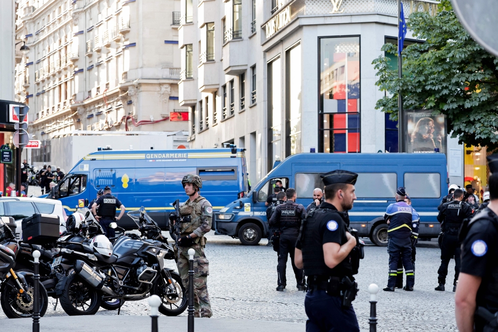Police officers, French gendarmes and a soldier secure the aera in front of Louis Vuitton store after a man attacked a police officer with a knife, on the Champs-Elysees avenue in Paris, on July 18, 2024. (Photo by Stephane De Sakutin / AFP)