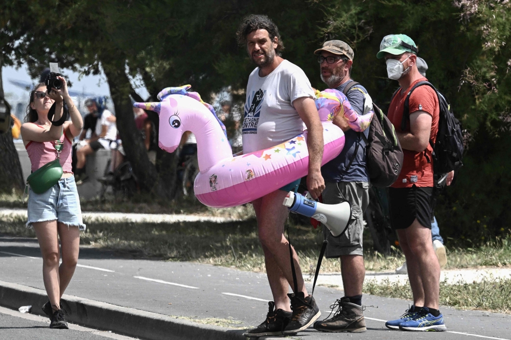 Julien Le Guet (C), spokesman for the 'Bassines Non Merci' (Reservoirs, No Thanks) movement, stands in a buoy featuring a unicorn, asking French Gendarmerie officers, not to charge during a protest against the construction of giant water reservoirs (Mega-bassines) in La Rochelle, western France on July 20, 2024. (Photo by Philippe Lopez / AFP)

