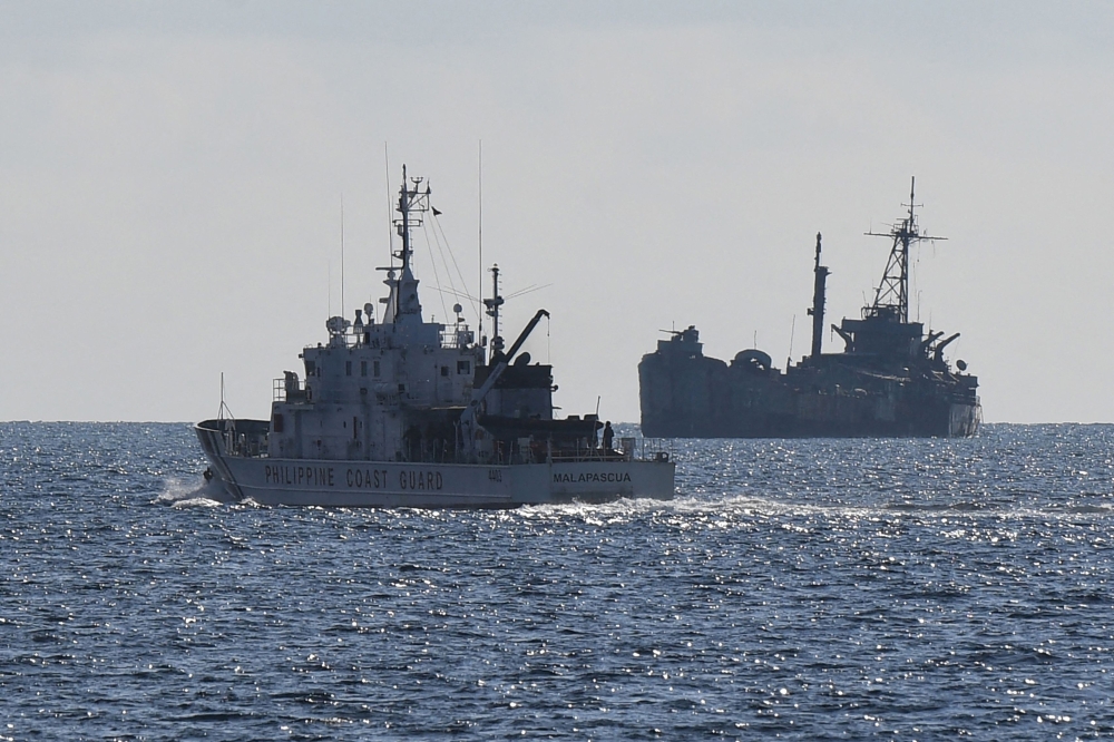 This file photo taken on April 23, 2023 shows Philippine coast guard vessel BRP Malapascua (L) patrolling near the grounded navy ship BRP Sierra Madre where Philippine marines are stationed to assert Manila's territorial claims at Second Thomas Shoal in the Spratly Islands in the disputed South China Sea. Photo by Ted ALJIBE / AFP