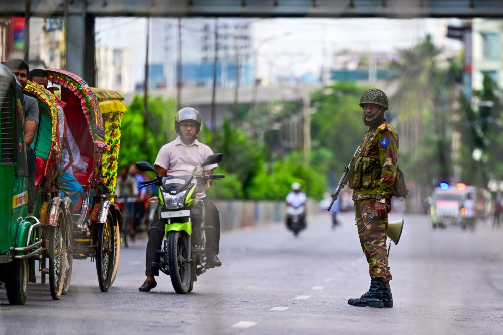 A Bangladeshi soldier stands guard along a street amid the anti-quota protests, in Dhaka on July 20, 2024. (Photo by Munir UZ ZAMAN / AFP)
