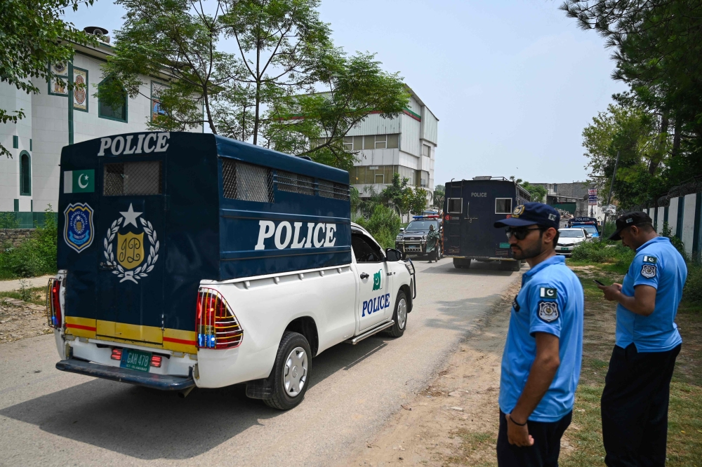 Policemen make way for prison van afer a security raid at the Pakistan Tehreek-e-Insaf (PTI) party's headquarters in Islamabad on July 22, 2024. (Photo by Aamir QURESHI / AFP)
