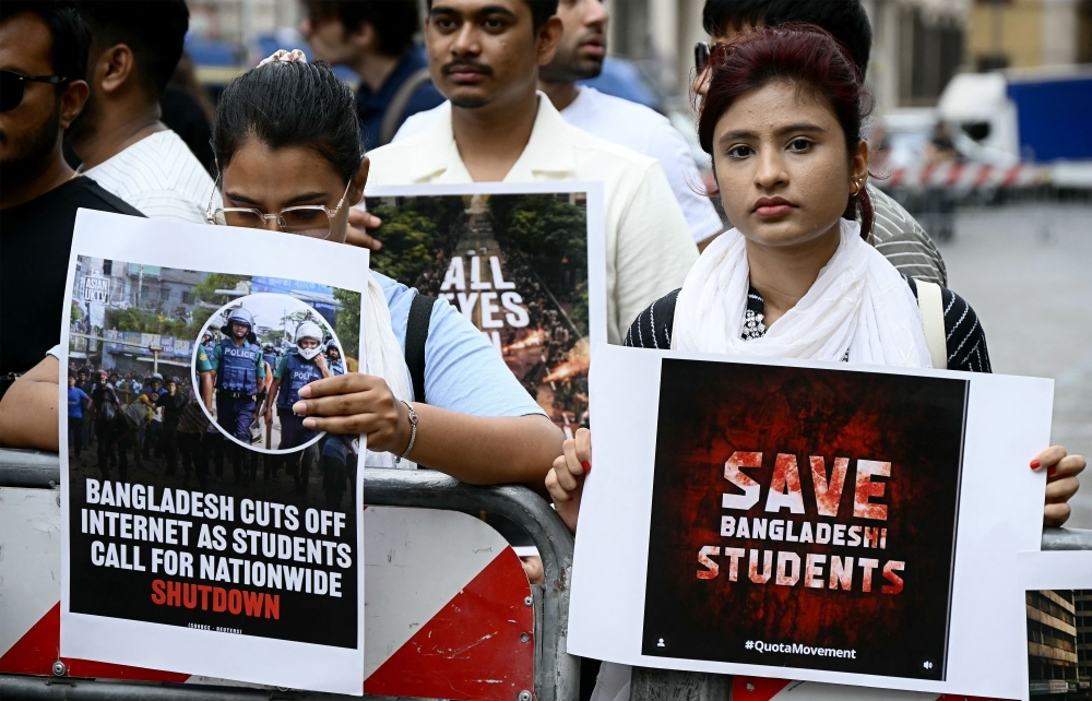 Students from Bangladesh hold placards as they demonstrate to ask the government to end the crackdown on protesters on July 22, 2024. (Photo by Filippo Monteforte / AFP)