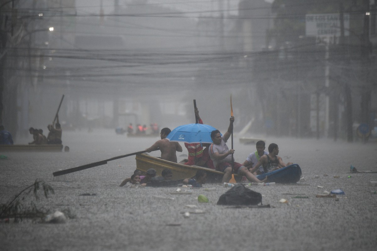 Rescuers paddle their boats along a flooded street in Manila on July 24, 2024 amid heavy rains brought by Typhoon Gaemi. Photo by Ted ALJIBE / AFP