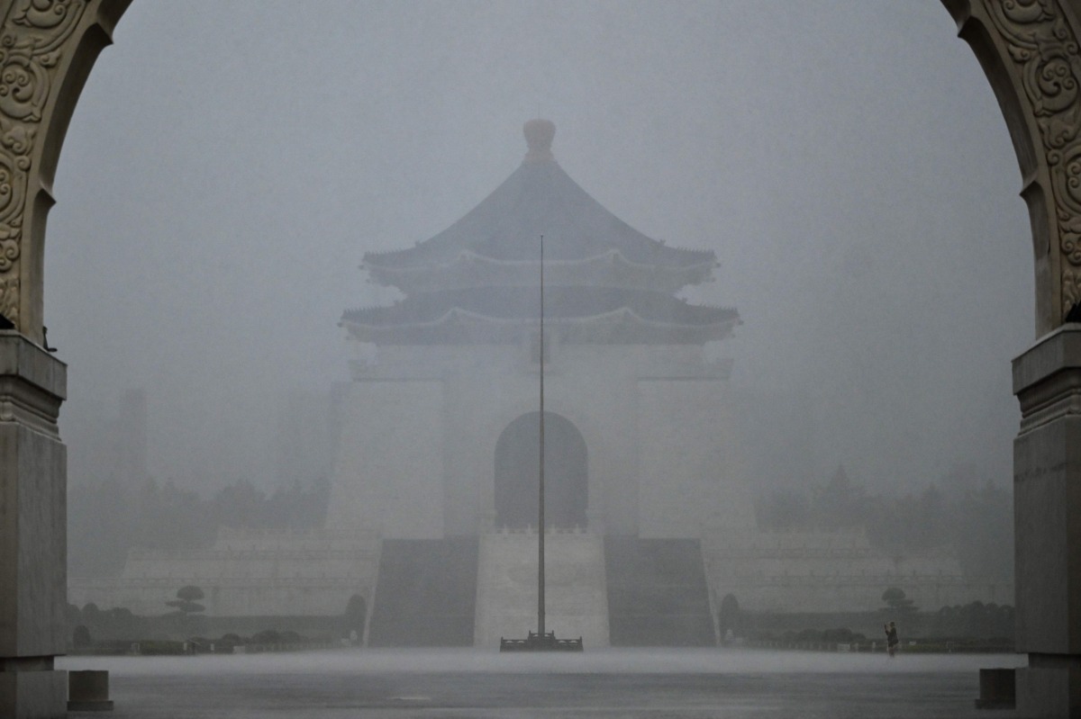 A visitor (bottom R) takes photographs in front of the Chiang Kai-shek Memorial Hall in heavy rain from weather patterns caused by Typhoon Gaemi in Taipei on July 24, 2024. (Photo by Sam Yeh / AFP)
