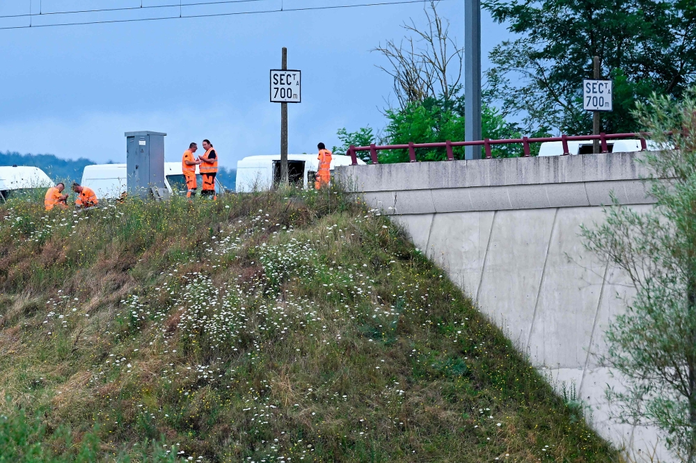 SNCF employees repair the scene of a suspected attack on the Eastern high speed railway network in Vandieres, north eastern France on July 26, 2024. (Photo by Jean-Christophe Verghaegen / AFP)